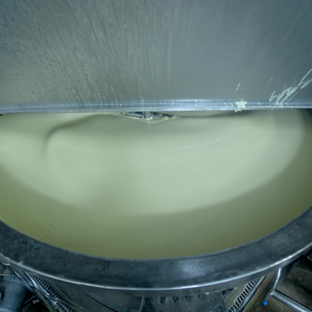 Industrial equipment for making butter. Modern container mixing butter at milk factory. Creamy dairy product in a tank