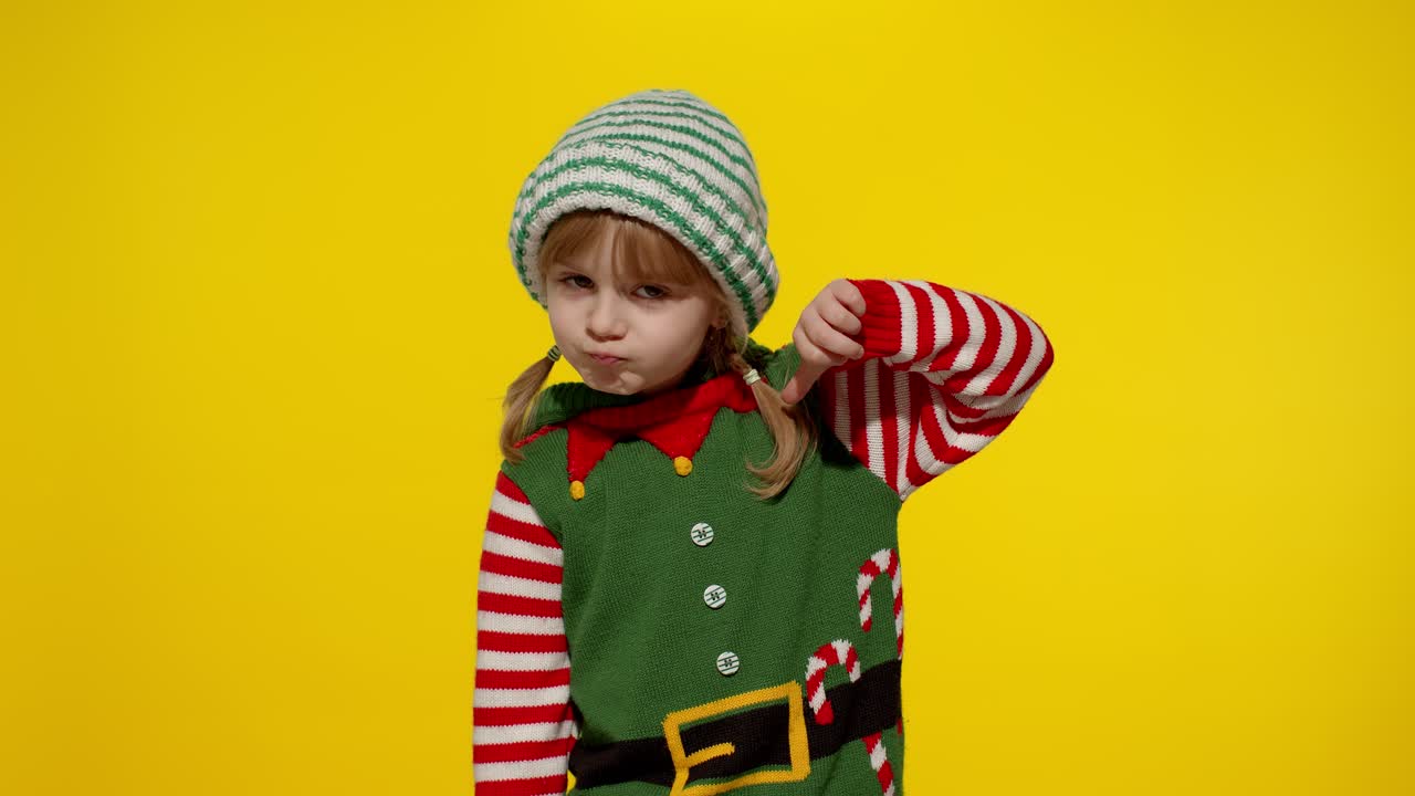 Malá holčička oblečená jako elf ukazuje palec dolů.