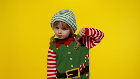 little girl dressed as an elf gives a thumbs down