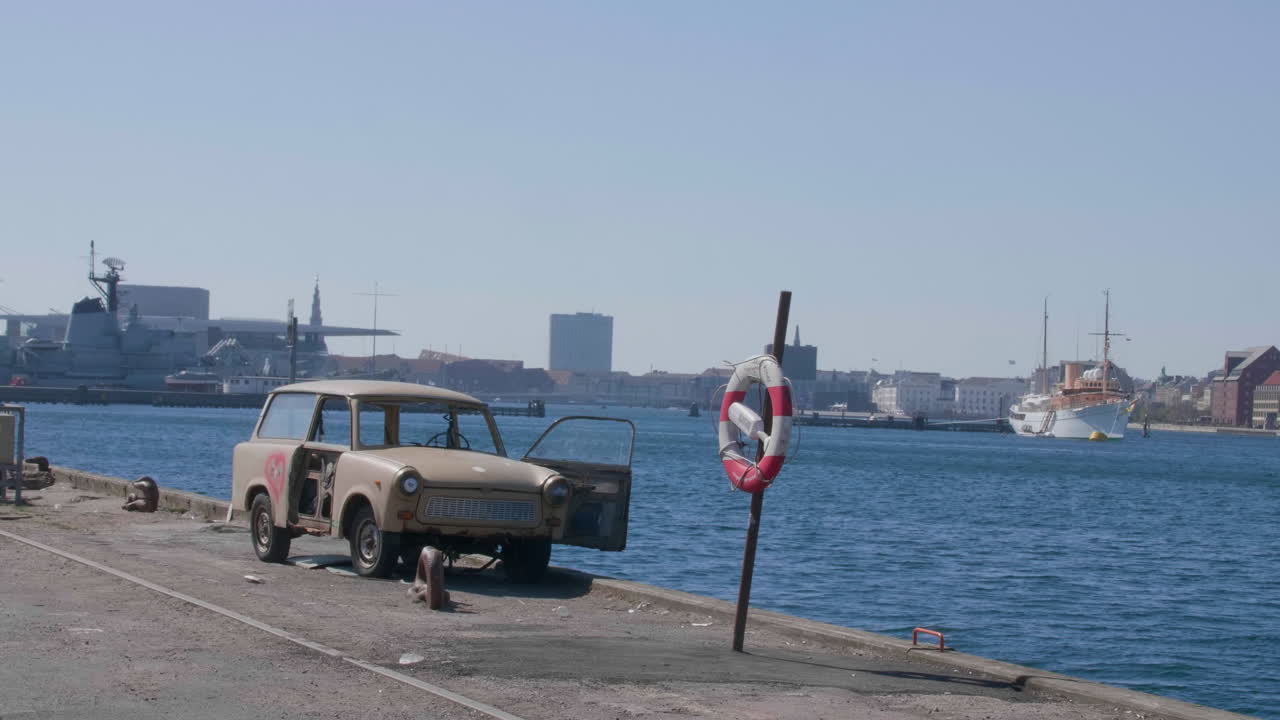 멀리 코펜하겐의 스카이라인과 함께 해안가에 버려진 자동차