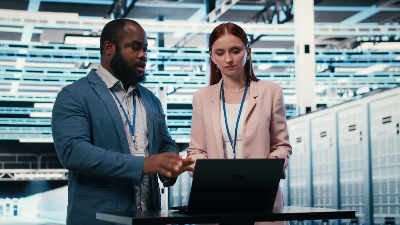 IT Professionals Discussing Data on Laptop in Server Room