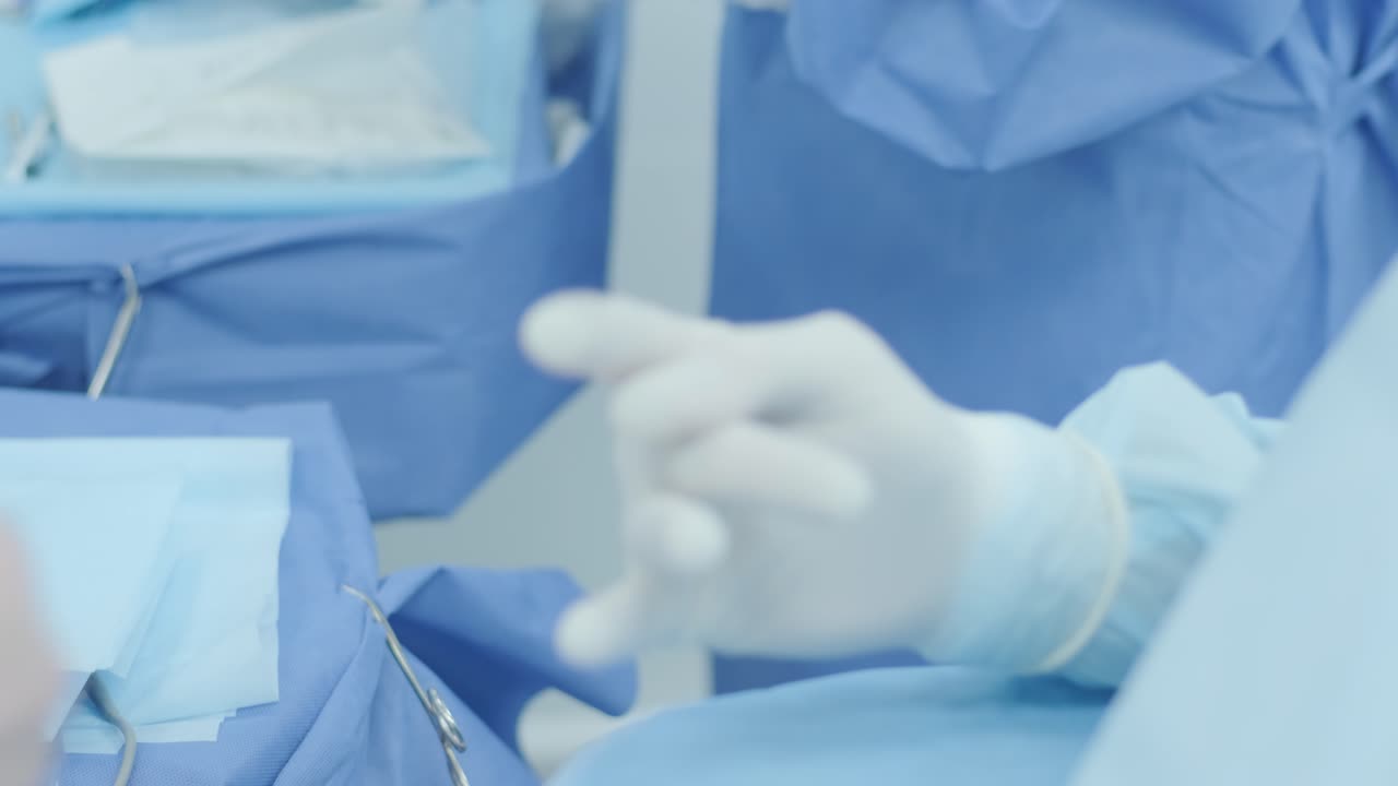 медсестра помогает хирургу надеть защитные перчатки перед операцией.