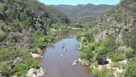 lush retreating aerial of rafters paddling on remote, rugged river