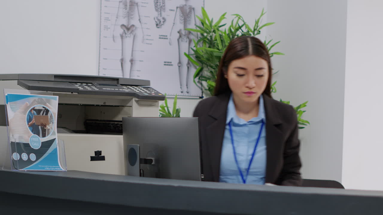 Woman working at a reception desk near a printer