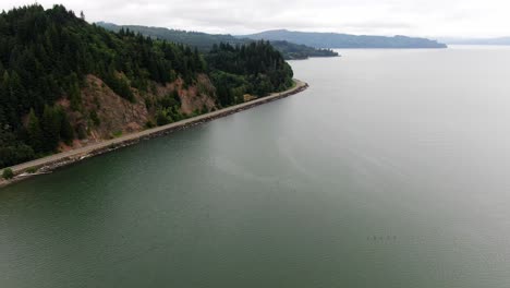 aerial dolly forward over columbia river coastline with car driving along coastal highway