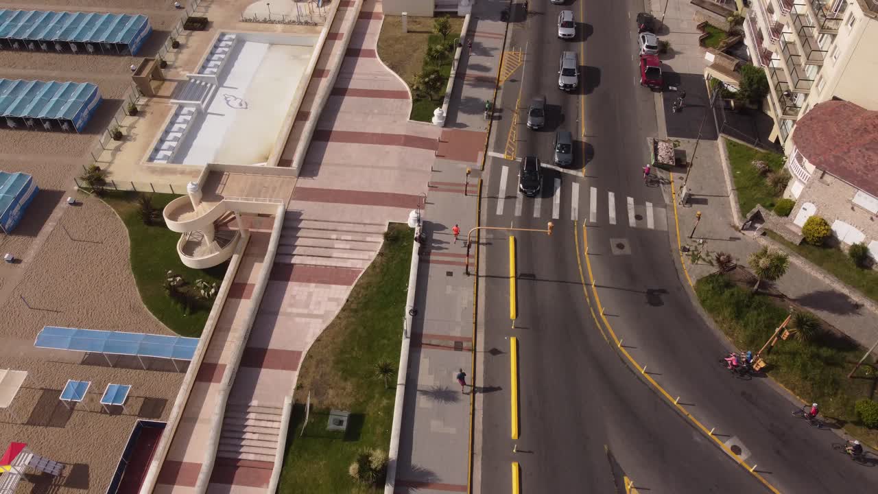 vista de arriba hacia abajo de un hombre corriendo en la calle de mar del plata en argentina en un día soleado en un entorno natural al lado de la carretera de vehículos