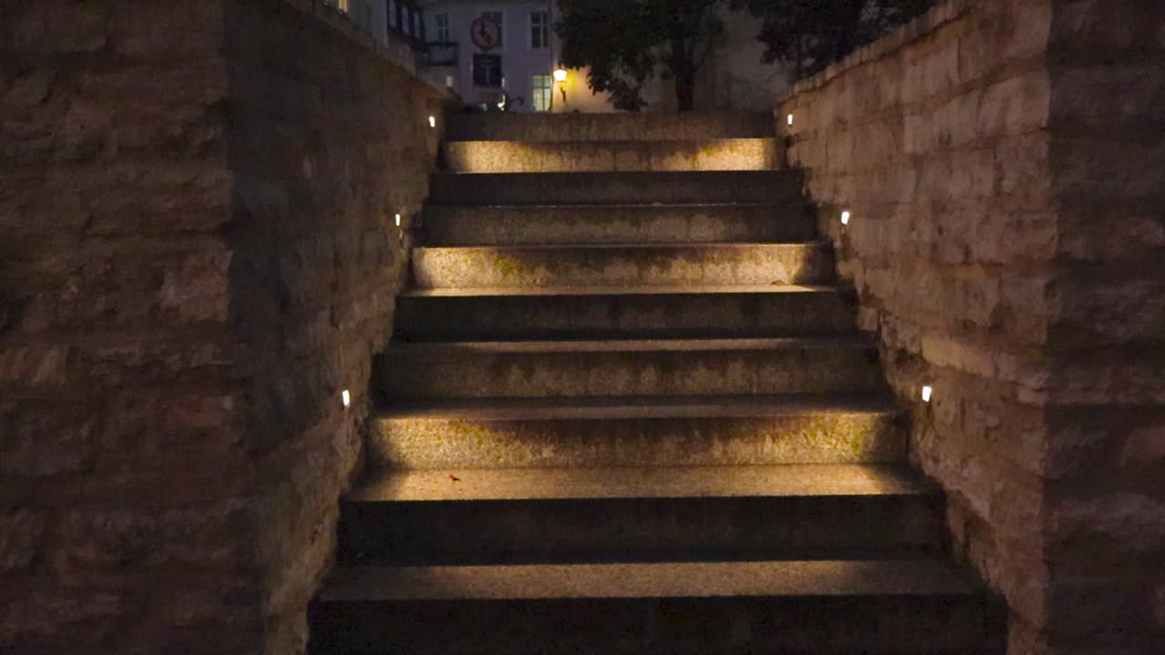 Gorgeous staircase or stairs in Tallinn old town in Estonia capital city that is made of stone and well and dimly lit with led light during night time or dusk. Good weather and medieval houses visible