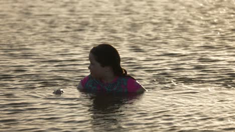 Are-young-girl-swimming-in-the-ocean-during-golden-hour-up-close-shot
