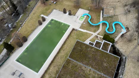 outdoor swimming pool closed for the season with dirty green water and empty water park slide