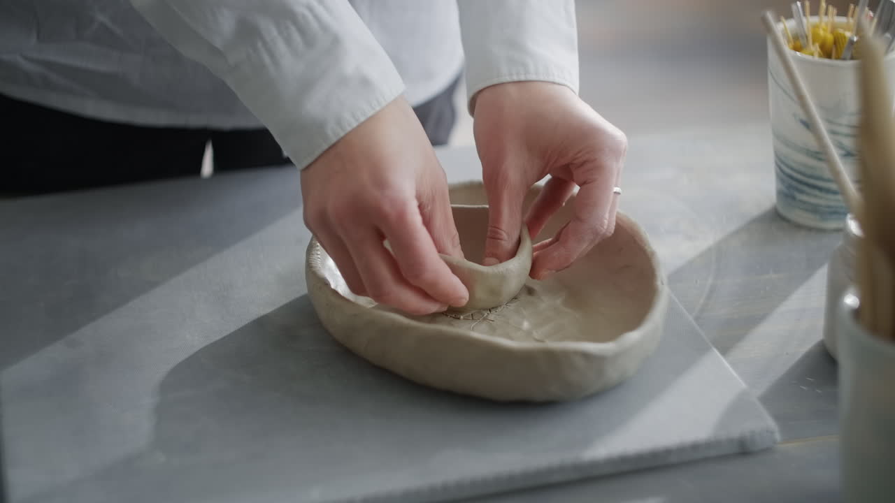 Hands shaping clay for a bowl