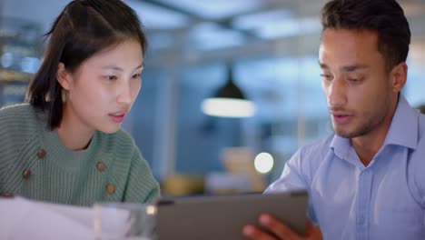 happy diverse male and female colleague discussing work and using tablet late at office