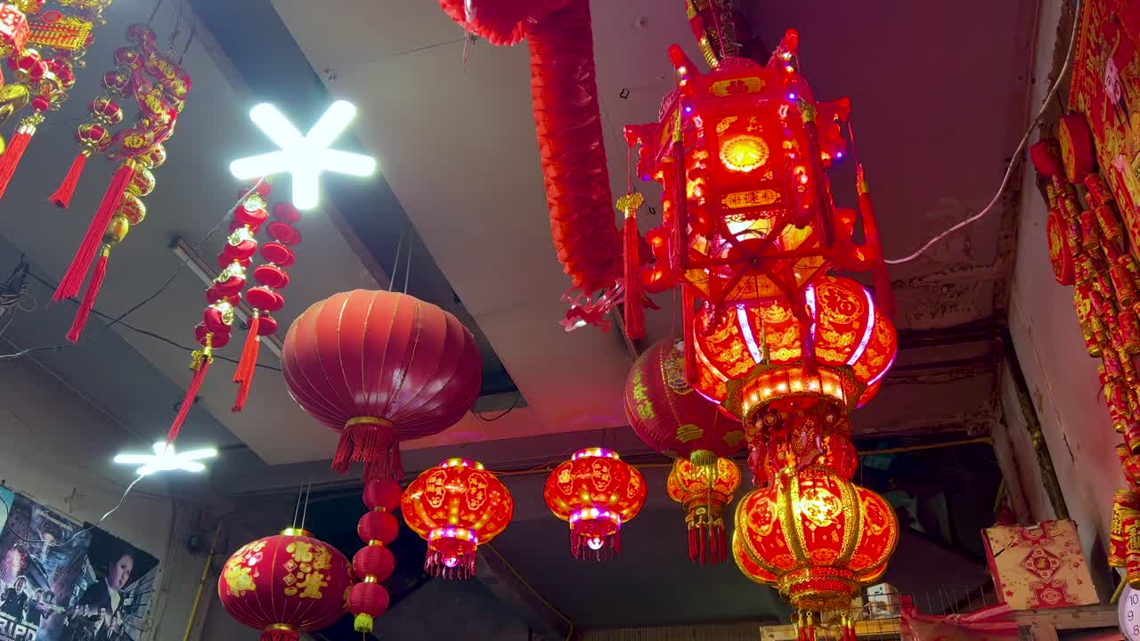 Bright red lanterns and festive decorations illuminate a bustling Chinatown street market in Bangkok, Thailand