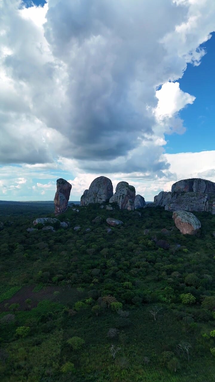 Stunning aerial shot of the famous Black Rocks of Pungo Andongo giant rock monoliths with a hiker standing on a high viewpoint against a blue sky in Malanje Province, Angola.