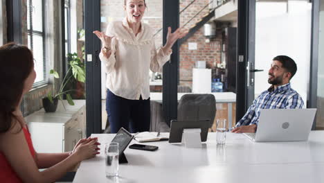 Young-Caucasian-woman-presents-enthusiastically-about-business-in-an-office-meeting