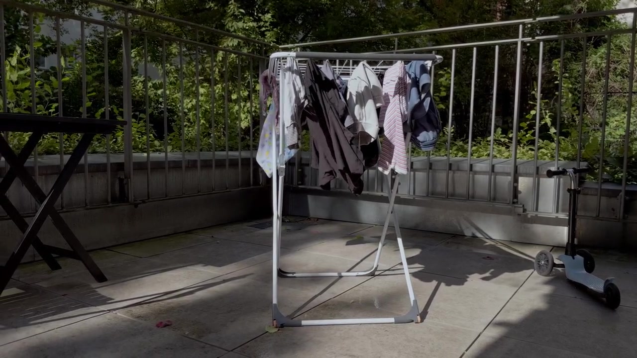 Family laundry naturally drying in sunlight and fresh air on a green urban terrace in Berlin, illustrating low-energy household habits and sustainable living.