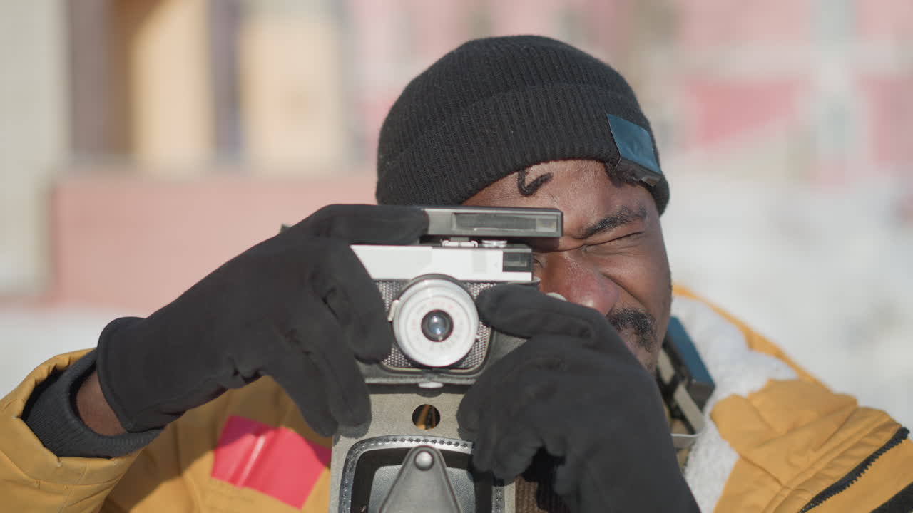 close up of videographer eyes fixed on camera adjusting lens capturing scene under bright sunny sky snowy urban backdrop with crisp light framing action wearing gloves and winter coat in cold weather