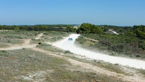 blue car driving on dusty off-road track at cape kamenjak near pula, croatia