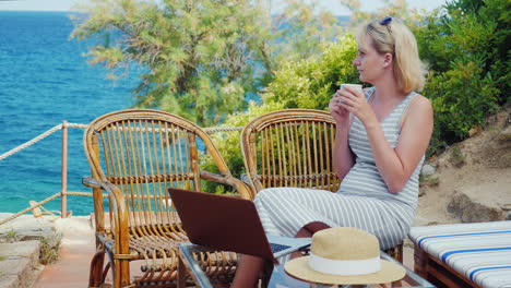 young woman sitting at the table with a laptop in front of sea view lady freelancer working at the b