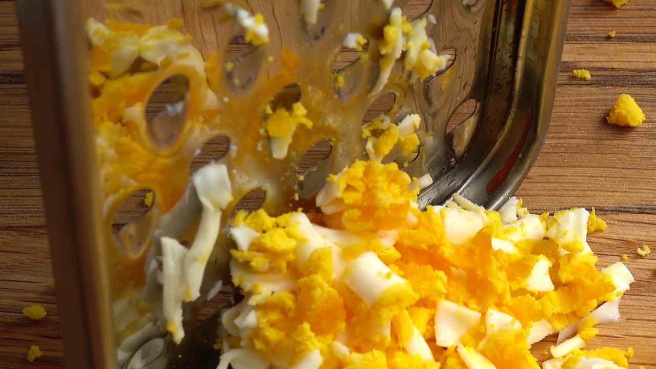 Il cuoco grattugia l'uovo. Lavoro del cuoco.