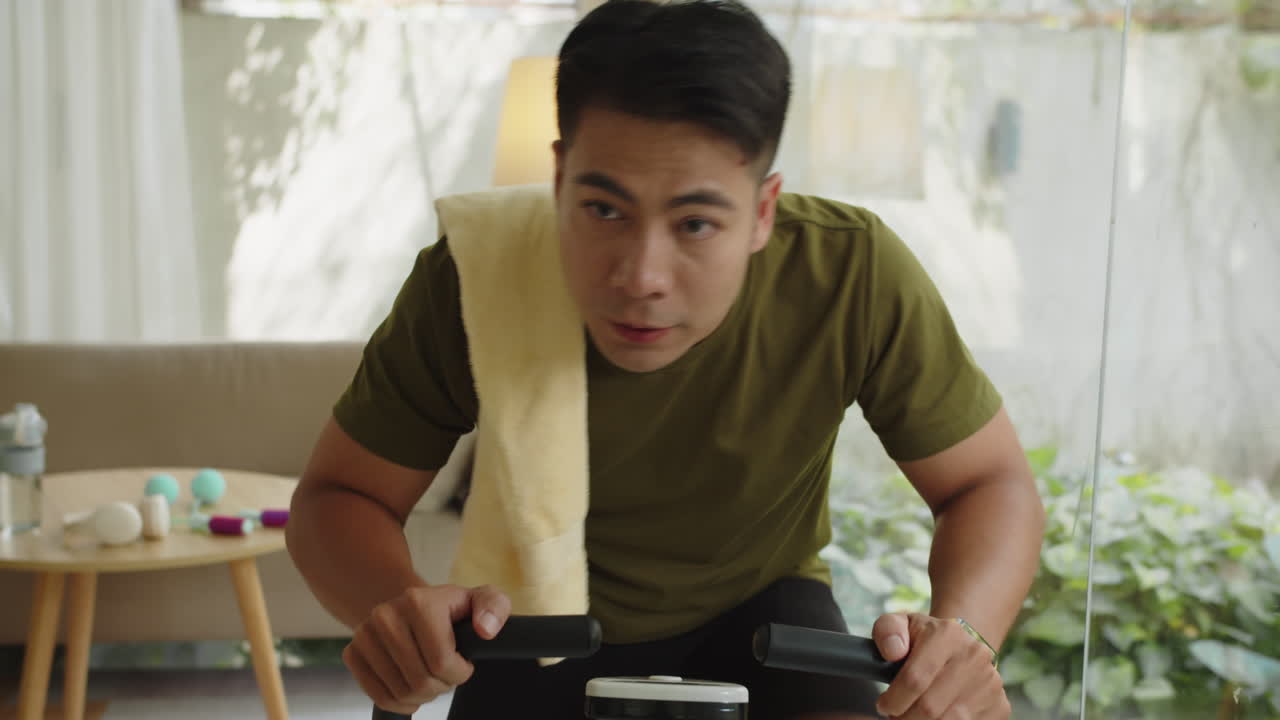 Asian Man Using Towel when Riding on Fitness Bike