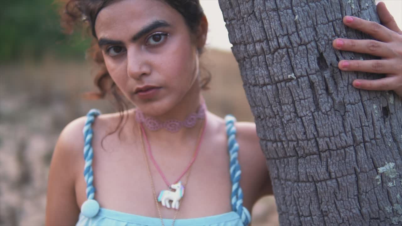 mujer con camisa azul sosteniendo cocotero en la playa