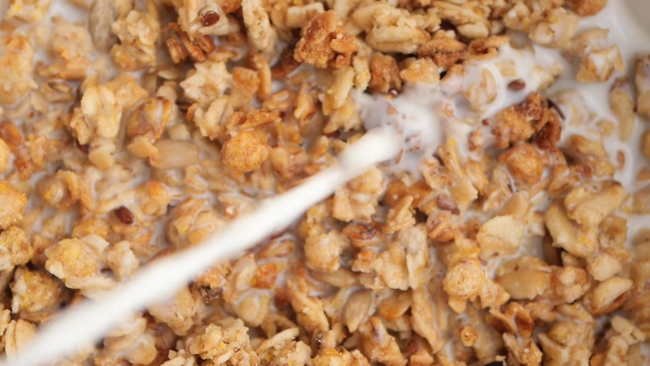 Versamento di latte al rallentatore in una ciotola di cereali granola