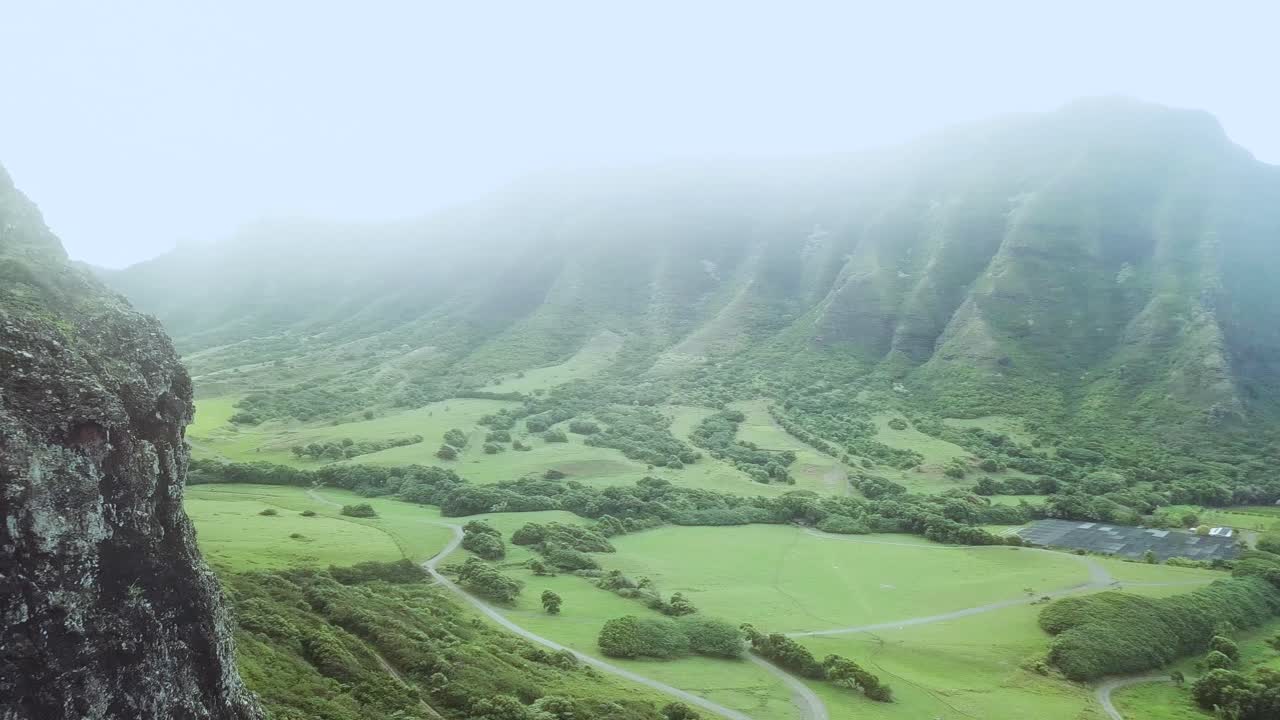 disparo de dron volando hacia atrás a lo largo de la cordillera de kualoa y revelando el hermoso rancho de kualoa