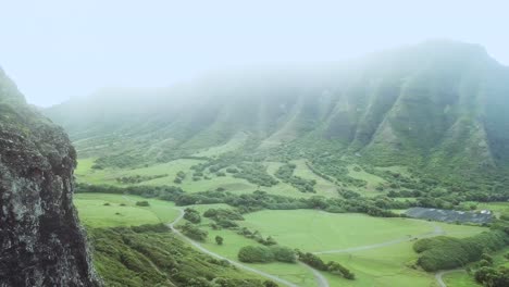 drone shot flying backwards along the kualoa mountain range and revealing the beautiful kualoa ranch