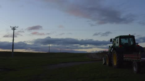 farm sunset with parked tractor on grass, clouds on horizon, telephone lines