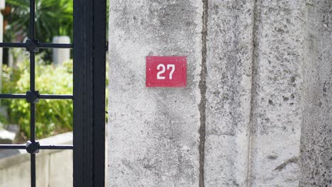 red number 27 sign on a stone wall