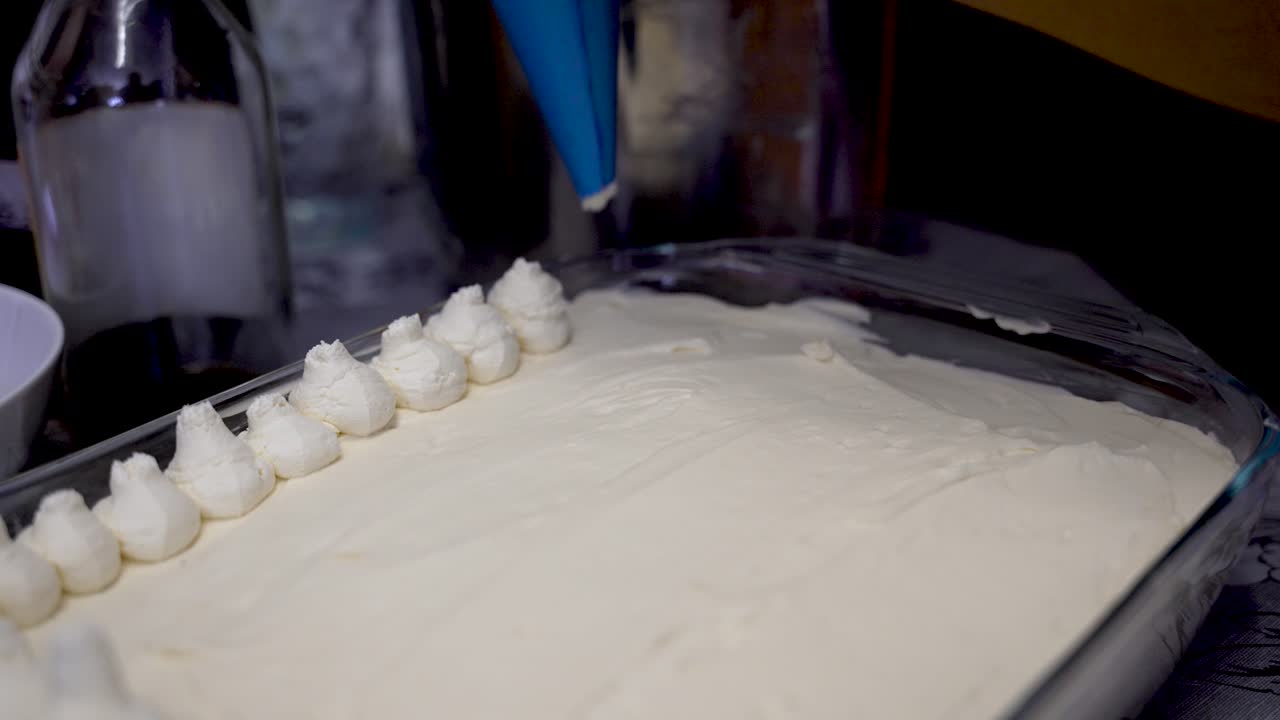 Baker Applying Fresh Cream Using Piping Bag To