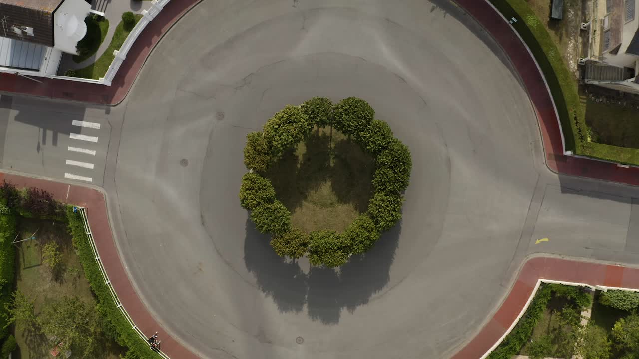 vista aérea de la rotonda de tráfico, círculo de tráfico con árboles verdes aceras naranjas y hierba verde por encima de las casas típicas francesas en deauville, francia. coche deportivo muscular blanco pasando por 4k uhd.
