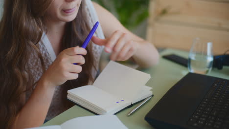 Close-Up-of-Female-Student-Writing-Notes