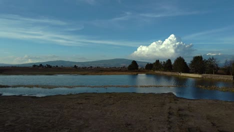 Traveling-truck-right-of-a-lonely-lake-with-mountains-in-the-background-parallax-effect-in-Almoloya-Mexico