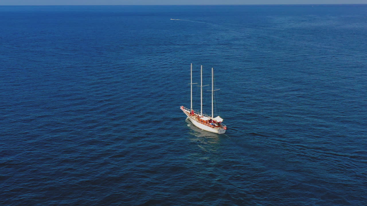 Aerial view of Lonely Sailing Boat, Drone view of a ship with canvas on the ocean. Fllowing ship in the middle of the ocean. Wooden mast.