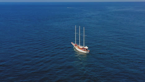 aerial view of lonely sailing boat, drone view of a ship with canvas on the ocean. fllowing ship in the middle of the ocean. wooden mast.
