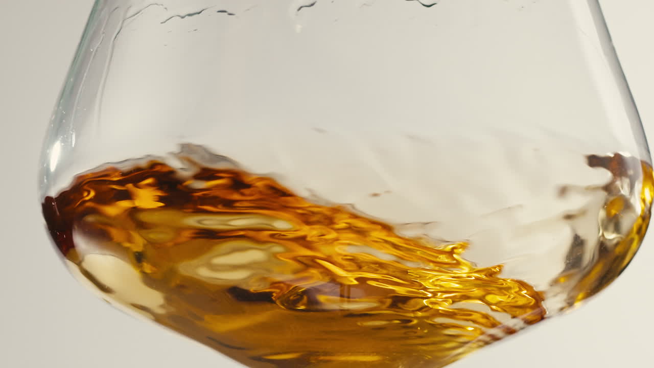 Orange or white wine bottle and glass against a sunset in a peaceful vineyard, pouring of ecological natural wine.