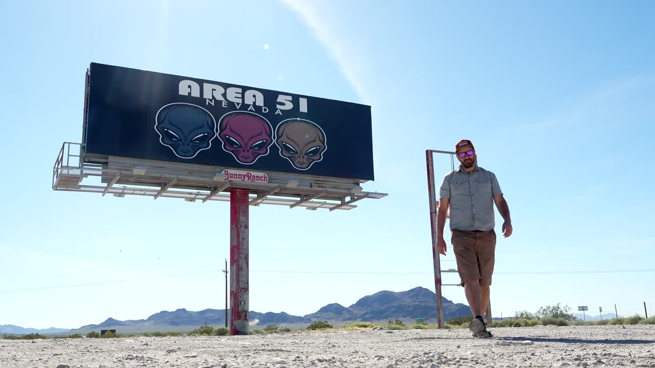 Người đàn ông đi ngang qua biển quảng cáo Area 51 Nevada trong sa mạc