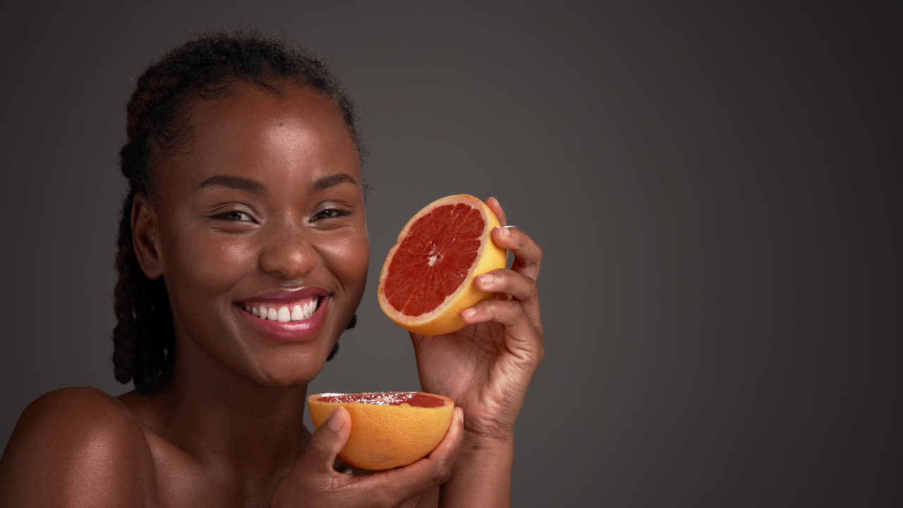 Vrouw lacht terwijl ze een grapefruit vasthoudt