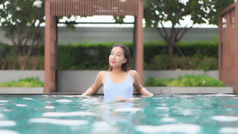 인피니티 풀 뒷벽을 따라 어슬렁거리는 예쁜 젊은 아시아 여성의 수위 샷