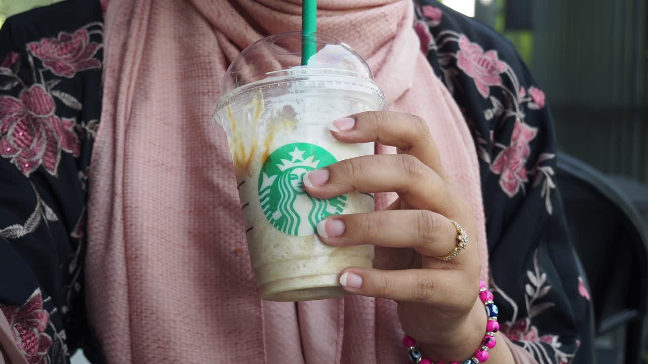 una mujer con un starbucks frappuccino.