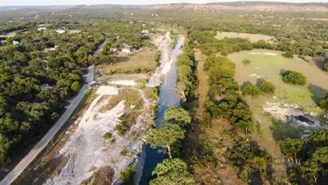 Bei-Sonnenuntergang-Den-Fluss-Hinunter-über-Große-Zypressen-Und-Hügelland-In-Der-Ferne-Fliegen---Luftaufnahmen-Des-Blanco-River-In-Wimberly,-Tx