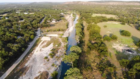 volando río abajo al atardecer sobre grandes cipreses y colinas en la distancia - imágenes aéreas del río blanco en wimberly, tx