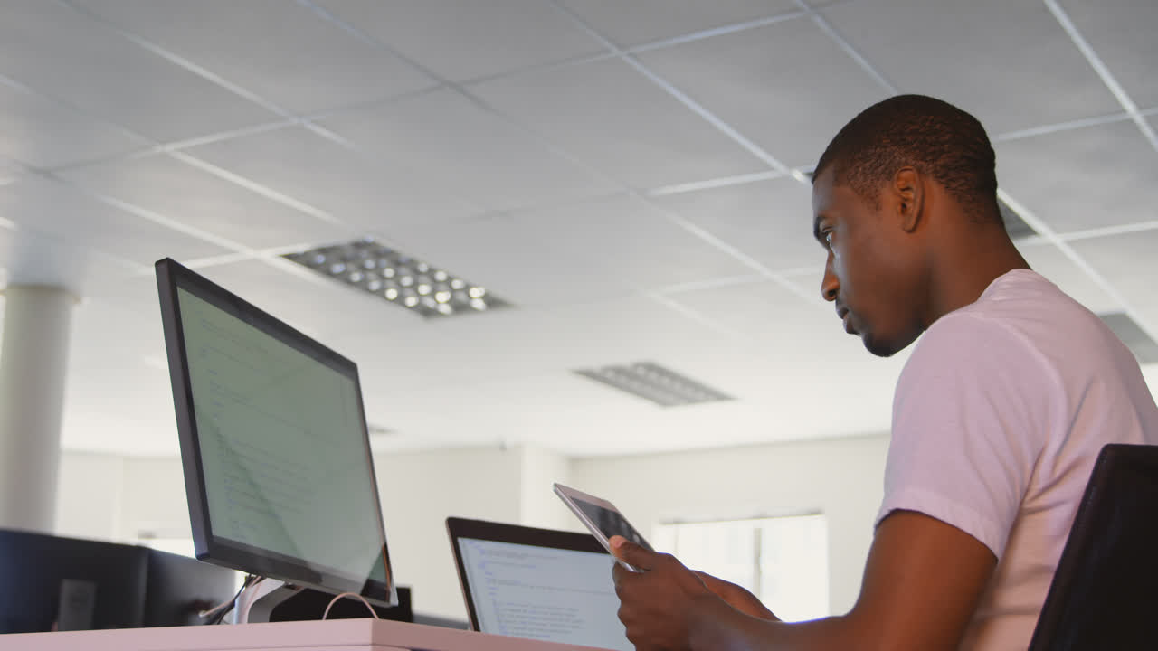 Side view of young black male executive working on digital tablet at desk in modern office 4k