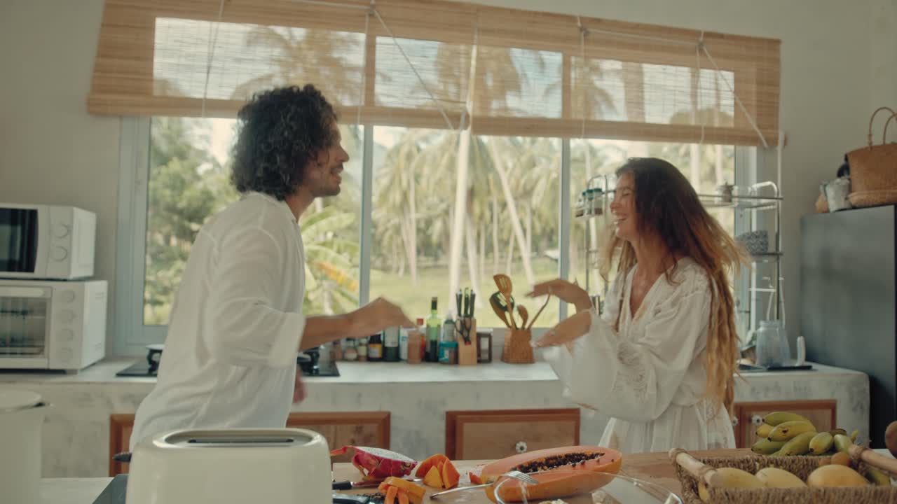 una pareja feliz bailando en la cocina.