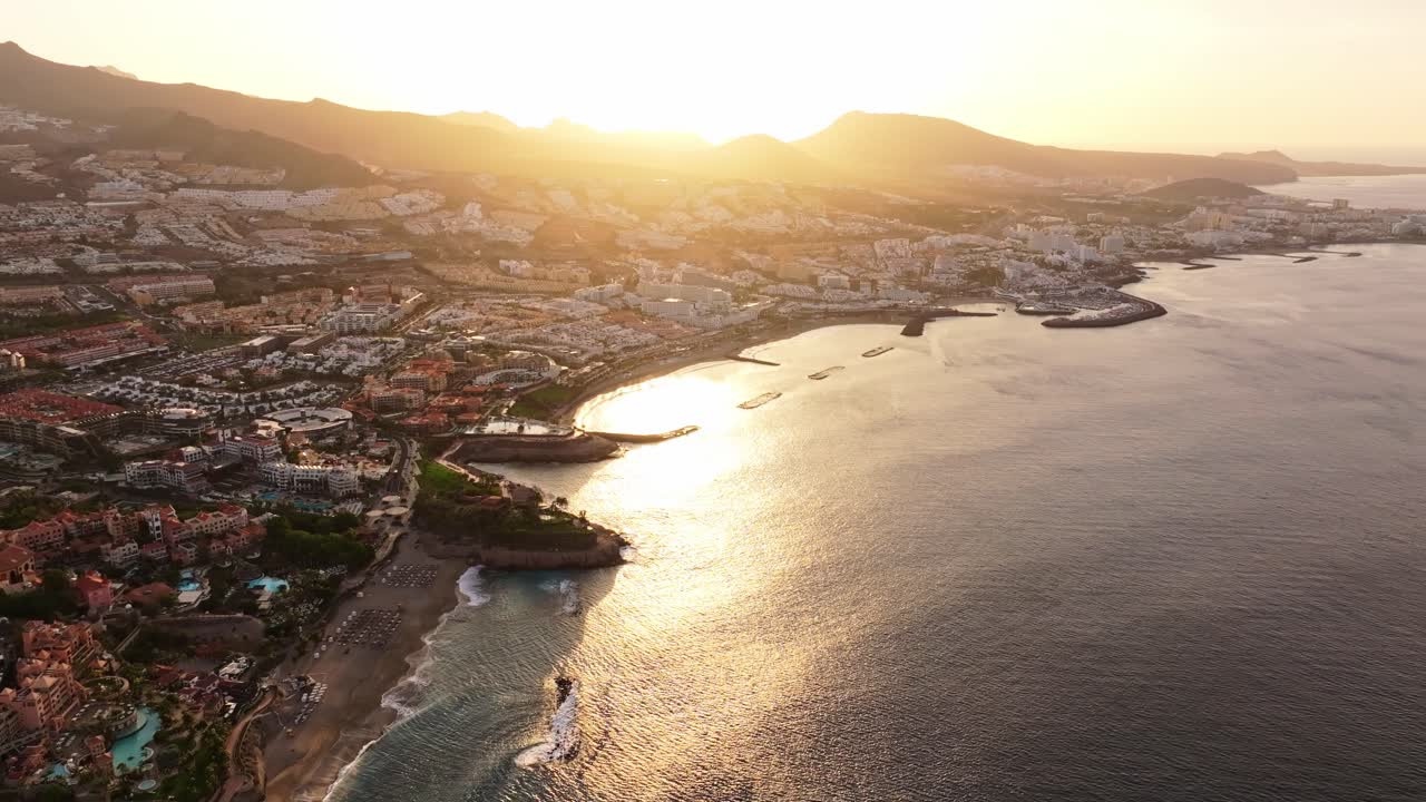 Soothing sunrise light washes over Costa Adeje coast, shimmering Atlantic waters