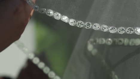 woman touches elegant wedding veil with glitter on edge