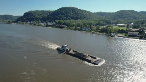 un remolcador empuja una sola barcaza de tierra hacia el norte en el río mississippi más allá de lansing, iowa