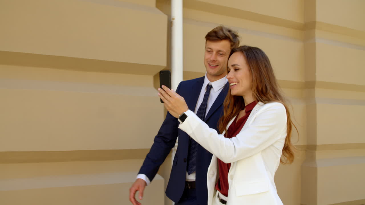 Partenaires commerciaux prospères ayant un appel vidéo sur un téléphone mobile à l'extérieur