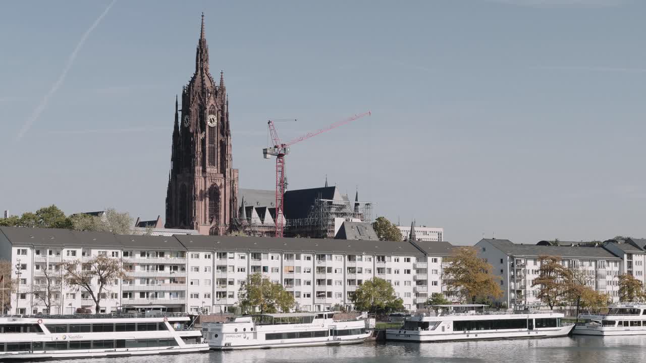Landscape view of Kaiserdom St. Bartholomäus church, Frankfurt with people walking at the park and Eiseiner Steg bridge as background